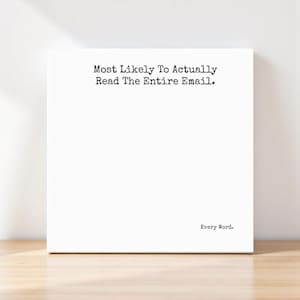 May include: A white canvas print with the text "Most Likely To Actually Read The Entire Email." and "Every Word." in a typewriter font. The print is displayed on a light wooden surface.