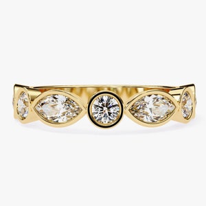 May include: A gold band ring with five clear gemstones. The center stone is round, and the four surrounding stones are marquise-shaped.