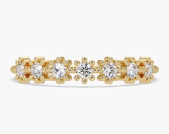 May include: A gold band ring with a row of small, round diamonds set in a delicate, geometric pattern.