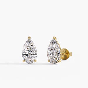 May include: A pair of stud earrings featuring pear-cut clear stones set in yellow gold. The earrings have a prong setting and a post back with the letters JF engraved on the back of the earring post. The stones are faceted and reflective.