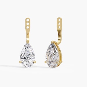 May include: A pair of gold earring jackets featuring pear-shaped clear stones set in a three-prong metal setting. Each jacket has a vertical gold post with three circular holes for adjustment and the letters JF engraved on the metal surface.