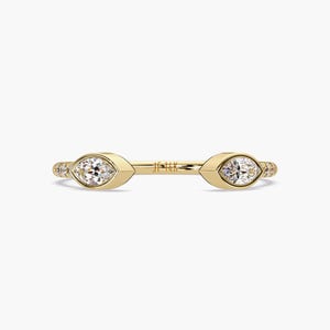 Könnte beinhalten: Ein goldener Ring mit zwei Marquise-Diamanten, die in der Mitte eingesetzt sind. Der Ring ist mit kleineren Diamanten entlang der Ringschiene verziert. Der Ring ist innen mit "14K" gekennzeichnet.