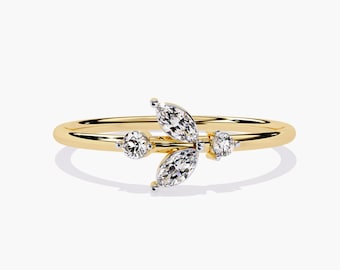 May include: A delicate gold ring featuring a cluster of three marquise-shaped diamonds. The diamonds are set in a prong setting and are surrounded by a thin band of gold.