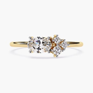 May include: A gold band ring with a large oval-shaped diamond and a cluster of smaller diamonds on the side.