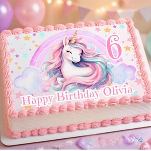 May include: A rectangular sheet cake with pink frosting borders, featuring a central illustration of a white unicorn with a rainbow mane, a gold horn, a pastel rainbow, clouds, and stars. The text reads 6 and Happy Birthday Olivia.