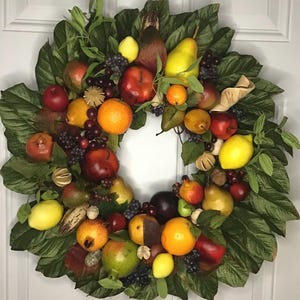 May include: A decorative wreath featuring a variety of faux fruits, including apples, pears, oranges, and lemons. The fruits are interspersed with green leaves and grapes, creating a vibrant and colorful display. The wreath is designed for seasonal home decor.