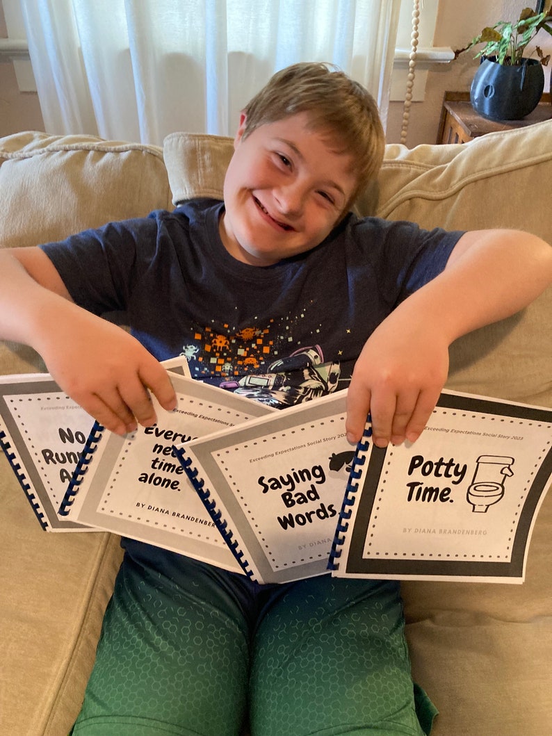 Op de afbeelding: Een jong persoon houdt vier sociale verhalenboeken vast. De boeken zijn getiteld "No Run Away", "Every Net Time Alone", "Saying Bad Words" en "Potty Time".