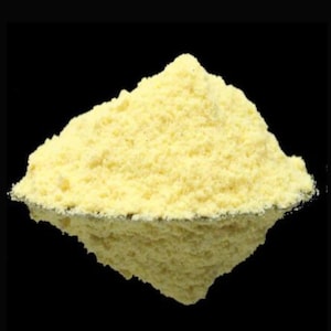 May include: A pile of yellow cornmeal powder on a black background.