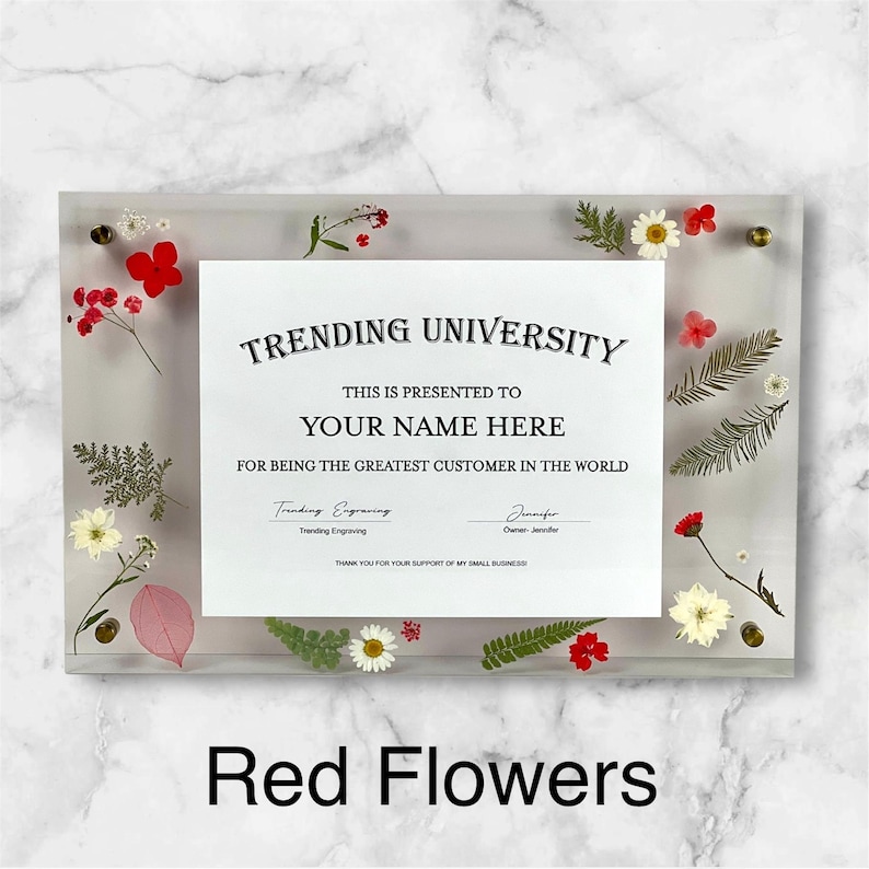 Puede incluir: Un marco acr&iacute;lico transparente con un certificado que dice "TRENDING UNIVERSITY" y "YOUR NAME HERE". El marco est&aacute; decorado con flores y vegetaci&oacute;n secas rojas, blancas y amarillas. El texto "Red Flowers" est&aacute; en la parte inferior.