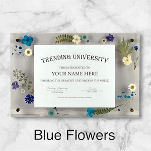 Puede incluir: Placa de acr&iacute;lico transparente con un certificado que dice "TRENDING UNIVERSITY" y "YOUR NAME HERE". La placa est&aacute; decorada con flores secas azules, blancas y moradas. El texto "Blue Flowers" est&aacute; en la parte inferior.