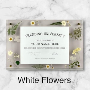 Puede incluir: Un marco rectangular de acr&iacute;lico transparente con un certificado que dice "TRENDING UNIVERSITY" y "YOUR NAME HERE". El marco est&aacute; decorado con flores blancas y vegetaci&oacute;n. El texto "White Flowers" est&aacute; en la parte inferior.