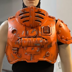 May include: Orange, weathered-look chest armor with a black undershirt. The armor features a series of vents, rivets, and mechanical details. The shoulder piece is rounded and has a series of rivets.