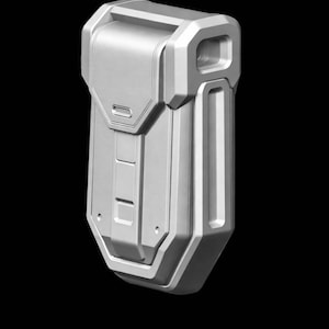 Può includere: Un astuccio o contenitore argentato dall'aspetto futuristico con un design geometrico. L'oggetto ha una forma rettangolare con un coperchio incernierato e una serie di rientranze rettangolari e quadrate. Lo sfondo è nero.