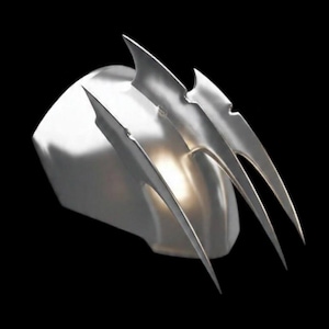 Puede incluir: Un casco plateado con tres protuberancias en forma de garra. La superficie es lisa y reflectante, sobre un fondo negro. El diseño es futurista e impactante.