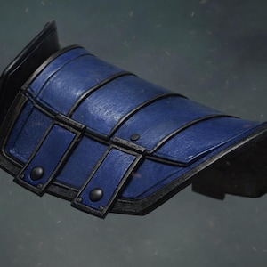 May include: A blue and black leather bracer, possibly for cosplay or historical reenactment. The bracer has a curved design with several horizontal straps and rectangular accents, secured with rivets. The edges are trimmed in black.