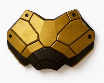 Puede incluir: Una pieza de arte mural geométrica con una combinación de colores dorados y negros. El diseño presenta una serie de formas angulares y segmentadas, creando una estética moderna y abstracta. La pieza está montada sobre un fondo blanco.