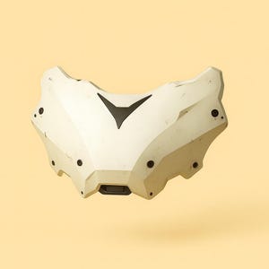 May include: A white, angular mask with a black chevron design and small black circular details. The mask has a textured surface and is set against a light yellow background.