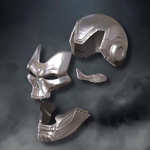 May include: A disassembled silver-colored skull mask, with separate pieces for the skull, jaw, and helmet. The mask has a detailed, futuristic design, with sharp angles and a metallic sheen. The pieces are arranged against a dark, smoky background.