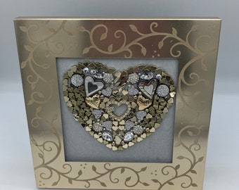 May include: A gold-toned frame with a decorative vine pattern surrounds a heart-shaped design made of small metal hearts, rhinestones, and other embellishments.