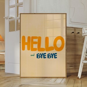 May include: A framed print with a light orange background and the text "HELLO and BYE BYE" in a bold, playful font. The text is in yellow and blue.