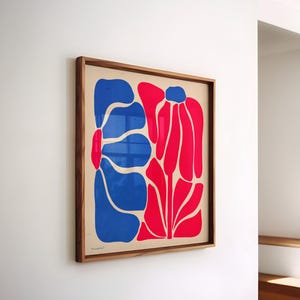 May include: A framed print of a stylized abstract floral design. The print features two large flowers, one blue and one red, on a cream background.