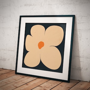 May include: A framed print of a stylized flower with five petals. The flower is a light orange color with a dark orange center. The background is a dark blue color.