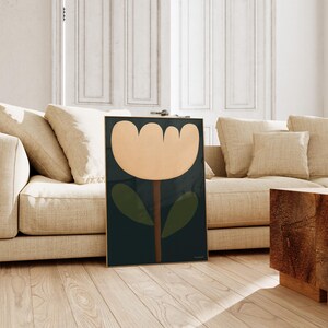 May include: A framed print of a stylized flower with a peach-colored blossom, green leaves, and a brown stem on a dark blue background.