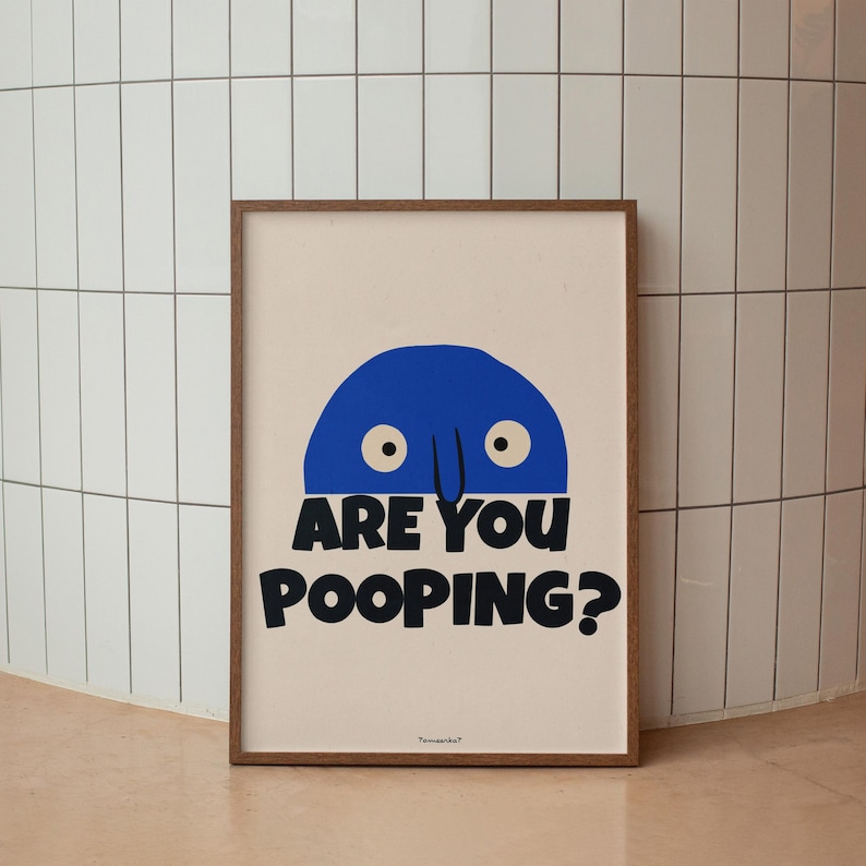 Op de afbeelding: Een ingelijst print met een blauw cartoonfiguur met grote ogen en een neus. De tekst "ARE YOU POOPING?" staat in het zwart onder het figuur.