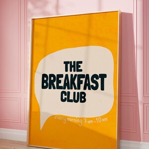 May include: A yellow poster with a speech bubble that says "THE BREAKFAST CLUB" in black text. The speech bubble also says "every morning 7am-10am" in smaller black text.