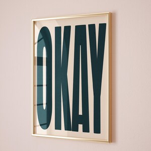 以下が含まれることがあります： クリーム色の背景に、太字の濃い青色の文字で「OKAY」と書かれた額装されたプリントです。