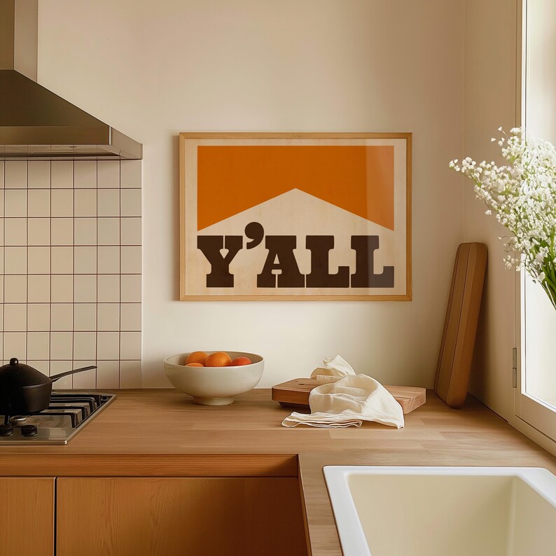 May include: A framed print with a brown background and orange geometric shape. The text "Y'ALL" is printed in black letters.