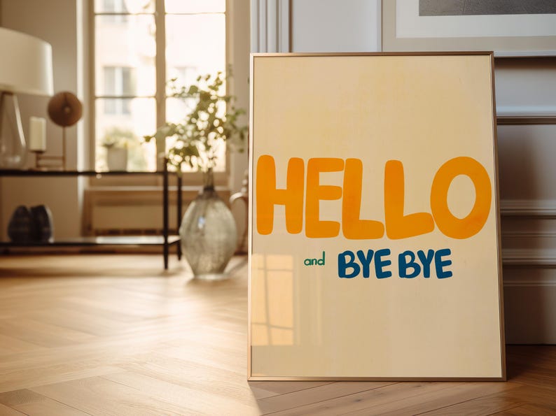 May include: A framed poster with a light yellow background and the words "HELLO and BYE BYE" in large, colorful letters. The word "HELLO" is in orange and the words "BYE BYE" are in blue.