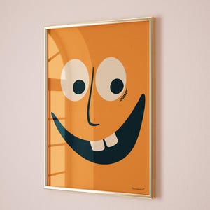 Può includere: Una stampa incorniciata di un viso di cartone animato con occhi grandi, un ampio sorriso e due denti visibili. Lo sfondo è di colore arancione pieno. La stampa è incorniciata in oro.