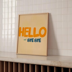 May include: A framed print with a yellow background and the words "HELLO" and "and BYE BYE" in blue and green text.