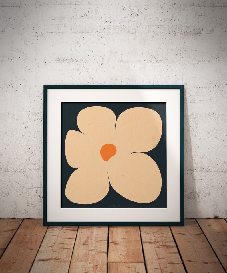 May include: A framed print of a stylized flower with five petals. The flower is a light peach color with a dark orange center. The background is a dark blue color.
