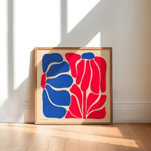 May include: A framed print of a stylized abstract floral design. The print features two large flowers, one in blue and one in red, against a cream background.