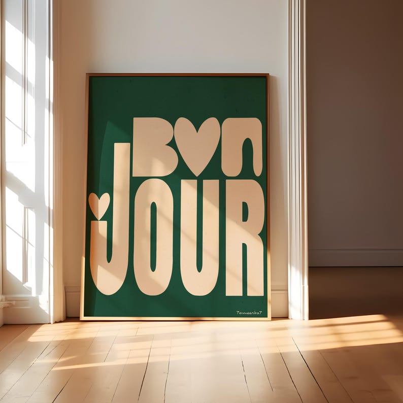 May include: A framed print with a green background and the words "Bon Jour" in a peachy-pink color. The letters are stylized and have hearts incorporated into the design.