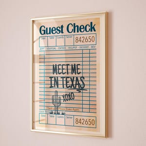 Puede incluir: Impresión enmarcada con un diseño vintage de "Guest Check". La obra de arte muestra el texto "MEET ME IN TEXAS" con una ilustración de cactus y "xoxo". La impresión está en un marco dorado.