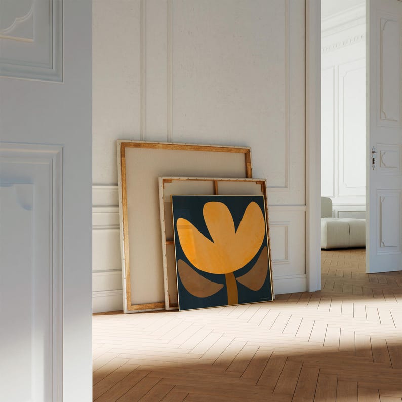 May include: A framed abstract art print with a yellow flower-like shape on a dark blue background. The print is leaning against a wooden frame.