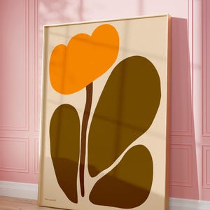 Peut inclure: Une impression d'art abstrait encadr&eacute;e repr&eacute;sentant une fleur stylis&eacute;e avec des p&eacute;tales orange et des feuilles brunes. Le fond est de couleur beige clair. L'impression est sign&eacute;e "remarkable" en bas &agrave; gauche.