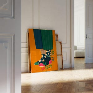 May include: A colorful poster with a pair of legs wearing mismatched socks. The socks are black with white polka dots and pink with white polka dots. The poster has a yellow background and the text "Be Unique" and "Be You" in pink and green.