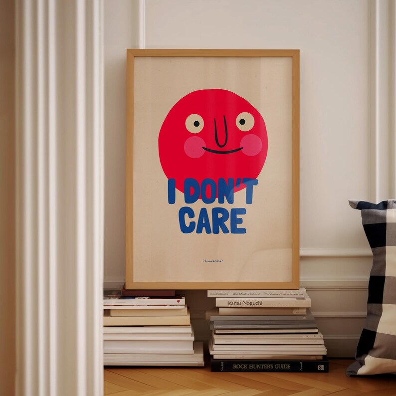 May include: A framed poster with a red circle face with a blue smile and the text "I DON'T CARE" in blue letters.