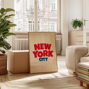 May include: A framed print with a light wood background and the text "NEW YORK CITY" in red and blue letters.