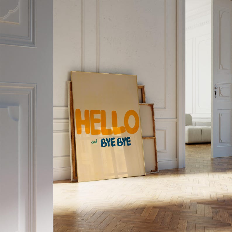 May include: A beige canvas print with the text "HELLO and BYE BYE" in yellow and blue lettering. The print is leaning against a white wall.