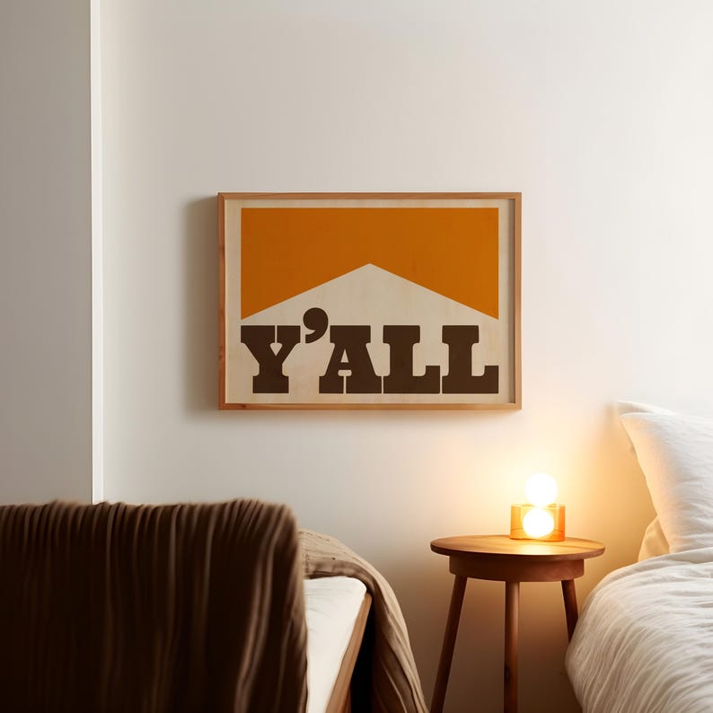 May include: A framed print with a yellow and white geometric design and the text "Y'ALL" in brown letters.