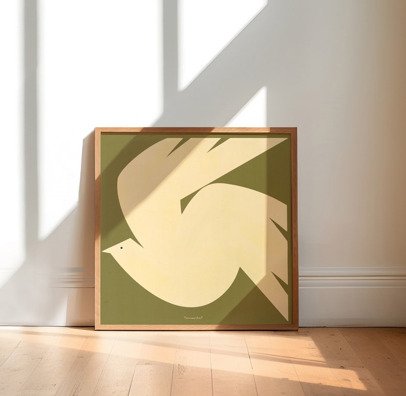 Puede incluir: Una impresi&oacute;n art&iacute;stica enmarcada que presenta una paloma estilizada en vuelo. La paloma es de color crema sobre un fondo verde oliva. La obra de arte est&aacute; encerrada en un marco de madera natural y descansa sobre un suelo de madera.