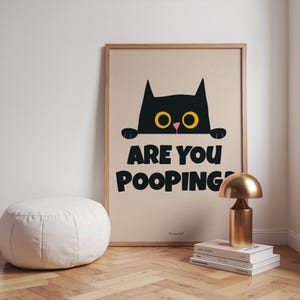 May include: A black cat with yellow eyes peeks over a beige background with the text "Are you pooping?" printed in black.
