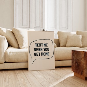 May include: A beige poster with a black speech bubble that says "Text me when you get home".