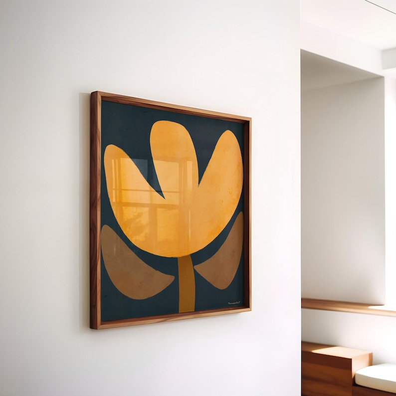 May include: A framed abstract art print featuring a stylized flower with yellow, brown, and orange petals on a dark blue background.