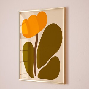 Peut inclure: Une impression abstraite encadr&eacute;e d'une fleur stylis&eacute;e avec des p&eacute;tales orange et une tige brune, sur un fond cr&egrave;me. Les feuilles sont d'un vert fonc&eacute;.
